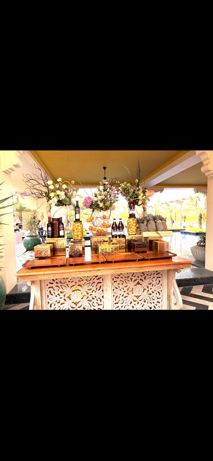 Wedding at Raffles Jaipur — carved wooden bar counter with elegant floral arrangement